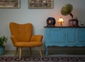 Retro orange armchair, vintage wooden light blue sideboard, old phonograph gramophone, vinyl records and illuminated table lamp