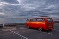 Retro orange van on the ocean beach.
