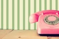 Retro pastel pink telephone on wooden table and abstract retro geometric pastel pattern Background. retro filtered image Royalty Free Stock Photo