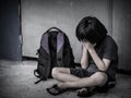 Sad Kid sitting on the floor with school bag waiting for parent. Royalty Free Stock Photo