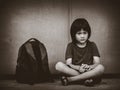 Sad Kid sitting on the floor with school bag waiting for parent. Royalty Free Stock Photo