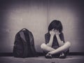 Sad Kid sitting on the floor with school bag waiting for parent. Royalty Free Stock Photo