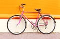 Retro pink bicycle stands over colorful orange