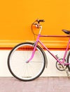 Retro pink bicycle stands over colorful orange background