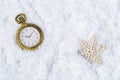 Retro pocket watch and wooden snowflake on snow background Royalty Free Stock Photo