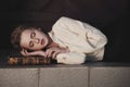 Retro portrait of a beautiful dreamy girl sleeping on the book outdoors. Soft vintage toning. Royalty Free Stock Photo