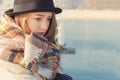 Retro portrait beautiful young sad girl in hat and coat stands on the dock Royalty Free Stock Photo