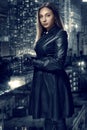 Retro portrait of inaccessible beautiful woman in black cloak stands against the background of the night city. Film noir Royalty Free Stock Photo