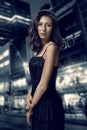 Retro portrait of inaccessible beautiful woman in black dress stands against the background of the night city. Film noir Royalty Free Stock Photo