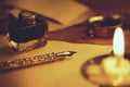 quill pen and inkwell on old parchment paper in candle light Royalty Free Stock Photo