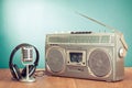 Retro radio and cassette player, headphones, microphone on wooden table front mint blue background. Vintage style filtered photo