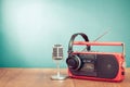 Retro radio cassette recorder, microphone and headphones on wooden table front mint blue background. Vintage style filtered photo