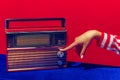 Retro radio. Female hand holding, touching radioreceiver  on blue and red background. Vintage, retro fashion Royalty Free Stock Photo