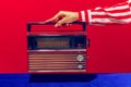 Retro radio. Female hand holding, touching radioreceiver  on blue and red background. Vintage, retro fashion Royalty Free Stock Photo