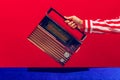 Retro radio. Female hand holding, touching radioreceiver isolated on blue and red background. Vintage, retro fashion Royalty Free Stock Photo