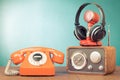 Retro radio, microphone and headphones, telephone on wooden table front mint blue background. Vintage style filtered photo Royalty Free Stock Photo