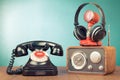 Retro radio, microphone, headphones and telephone on wooden table front mint blue background. Vintage style filtered photo Royalty Free Stock Photo