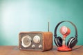 Retro radio, microphone and headphones on wooden table front mint blue background. Vintage style filtered photo