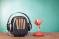 Retro radio, microphone and headphones on wooden table front mint blue background. Vintage style filtered photo