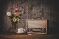 Retro radio receiver are still life with coffee cup and flower vases