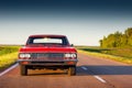 Retro red car standing on asphalt road at sunset Royalty Free Stock Photo
