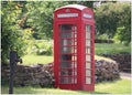 Retro red phone box in a country lane. Royal creat on top Royalty Free Stock Photo