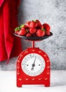 Retro red scales with a handful of fresh ripe organic strawberries.