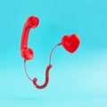 Retro red telephone handset connected to red heart on pastel blue background. Pop art, Vintage aesthetic 80s or 90s. Love
