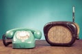 Retro rotary telephone and old radio on wooden table front mint blue background. Vintage style photo Royalty Free Stock Photo