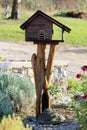 Retro rustic newly made decorative wooden birdhouse made in shape of wooden log cabin with front porch on top of tree stump Royalty Free Stock Photo