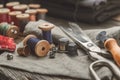 Retro sewing items: tailoring scissors, cutting knife, thimble, wooden thread spools, cushion for including pins, sewing accessori