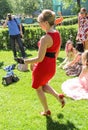 A dancing lady in red on a green lawn.