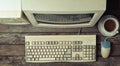 Retro stationary computer on a rustic wooden desk, vintage workspace. Monitor, keyboard, computer mouse, top view, flat lay.