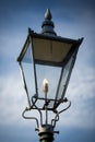 Retro street lamp shining against cloudy sky background Royalty Free Stock Photo