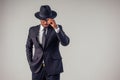 Retro style African american business man mafia model in dark suit and black hat in studio on white background
