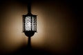 Retro style black lamp on yellow wall. Lamp illuminating wall in the darkness. Copy space Royalty Free Stock Photo