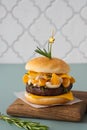 Retro style burger with beef cutlet, cheese and tangerines on a wooden board on a plain background