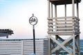 Geometry of striped white lifeguard tower made from wooden planks and round shaped bike parking sign made from cutout plywood Royalty Free Stock Photo