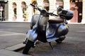 retro style metallic silver japanese scooter or moped parked on asphalt road. old stucco house exterior background Royalty Free Stock Photo