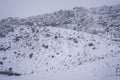 Retro style photo of a rocky slope in heavy snowfall. Blizzard in the mountains. Extreme winter weather Royalty Free Stock Photo