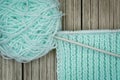 Retro-style photo of a woolen yarnroll, knitting needles, and knitwork in progress on wooden background