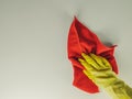 Retro style top view of yellow rubber glove hand and red rug wipe while cleaning a white surface during house domestic chores