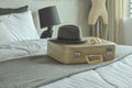 Retro style travel bag, hat and sunglasses on bed in hotel guest