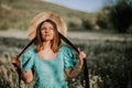 Retro styled woman on fluffy dandelions field, amazing fantasy portrait. Romantic elegant lady with straw hat on nature