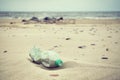Retro stylized picture of an empty plastic bottle left on a beach. Royalty Free Stock Photo
