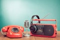 Retro telephone, radio and cassette player, headphones, microphone on table front mint blue background. Vintage style photo