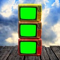 Retro television with green screen on wooden deck with clouds sky
