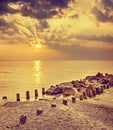 Retro toned dramatic sunset over beach and rocky pier Royalty Free Stock Photo