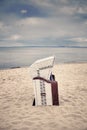 Retro toned hooded wicker chair on empty beach. Royalty Free Stock Photo