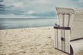 Retro toned hooded wicker chair on empty beach. Royalty Free Stock Photo